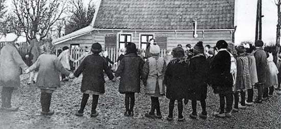 Leerlingen van de lagere school te Ursem spelen in de jaren dertig op het schoolplein naast de sigarenwinkel van Toon Vendel.