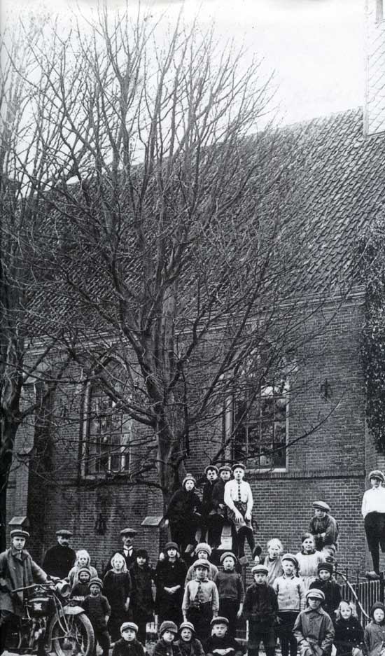 Op deze foto van omstreeks 1912 zijn de leerlingen van de openbare lagere school van Oosterleek verzameld voor de kerk.