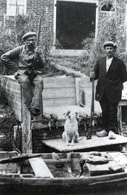 De gebroeders Dirk en Cornelis de Vries uit Andijk poseren voor hun schuit, waarmee zij naar &lsquo;de bouw&rsquo; konden varen.
