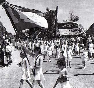 Adspiranten van de GV Turnlust Andijk lopen omstreeks 1960 mee in een optocht door hun dorp.