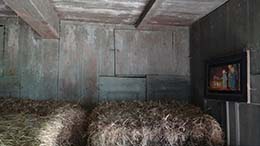 Woonkamer, de houten betimmering is zichtbaar achter de hooibalen.