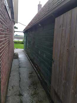 De steeg tussen de woning en de schuur.