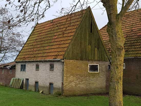 Te zien zijn de muren van witte steen, de drie luiken en de ramen en het dak van de schuur.