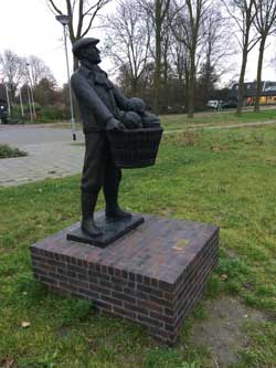 De tuinder met zijn koolmand voor de borst staat aan de rand van de Vroonermeerplas bij Sint Pancras.