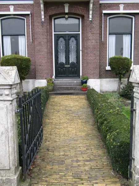  Pad met gele steentjes en voordeur.