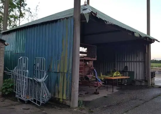 Oude vijzel op erf achter een boerderij.