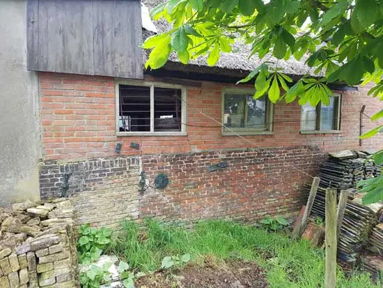 Achterkant met onderaan de oude muur gemaakt van stenen uit de in 1881 gesloopte boerderij.
