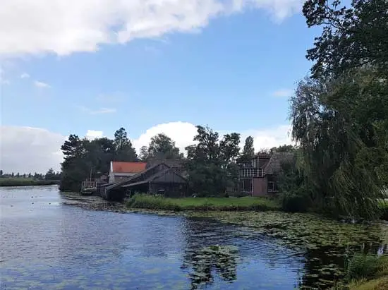 Een idyllisch gezicht op woning, schuitenhok en schuren.