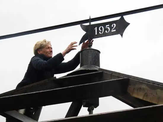 De ladder op en de windvaan wordt geplaatst.