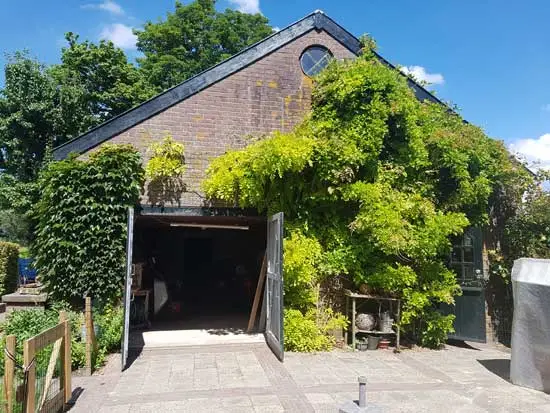 De zuidzijde van de schuur met dubbele deur en in de gevel een rond raam, 2022.