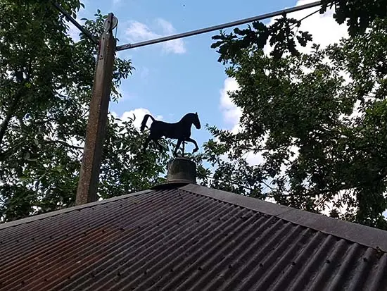 Bovenop het dak een windvaan met een paard.