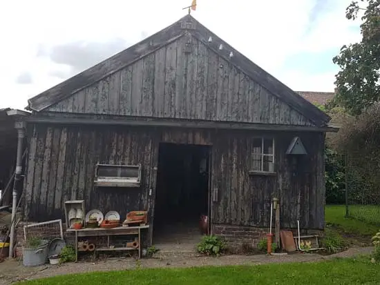 Ingang oudste schuur. Drie wanden van hout, het dak van golfplaten.